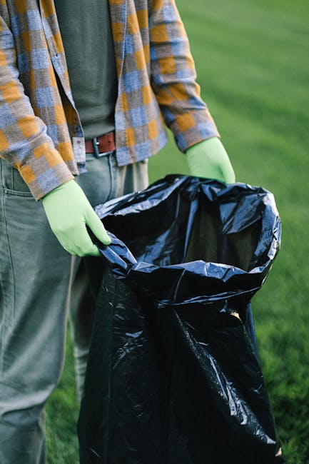 A tall blue plastic rubbish bin with a closed lid is positioned outdoors on a grassy area, with a small yellow sticker on its front that reads 'FIGHT BACK!' in black text with a lightning bolt graphic